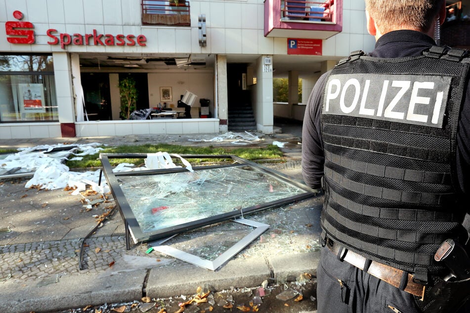 Nach einem Überfall sichert ein Polizeibeamter das Umfeld vor einer Sparkassenfiliale in Berlin.
