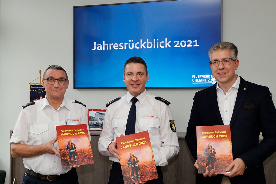 Der Amtsleiter der Feuerwehr Chemnitz, Rene Kraus (49, M.), und der Vorsitzende des Stadtfeuerwehrverbandes, Thomas Jacob (55, l.), übergeben das Jahrbuch der Chemnitzer Feuerwehr 2021 an Bürgermeister Ralph Burghart (52).
