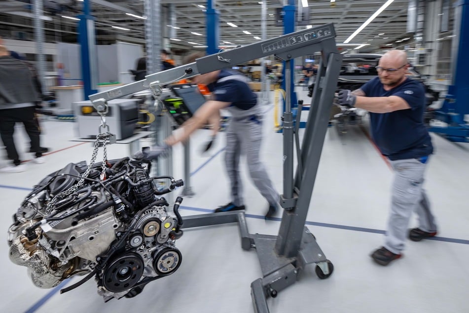 Das Herz hängt am Haken: Mitarbeiter transportieren einen ausgebauten Motor durch die Werkhalle.