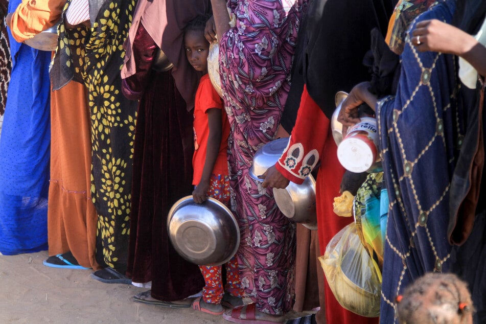 A Sudanese girl who fled El-Fasher lines up with other women to receive a meal at the Al-Afad camp for displaced people in the town of Al-Dabba, northern Sudan, on November 20, 2025.