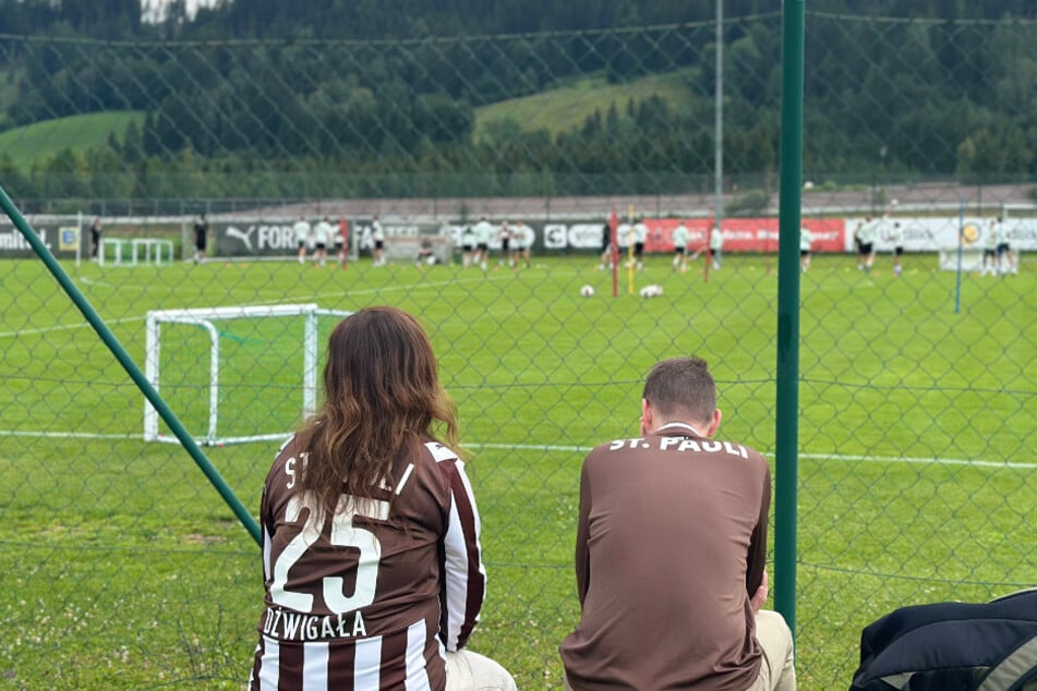 Die mitgereisten Fans beobachten das Training der Mannschaft ganz genau.