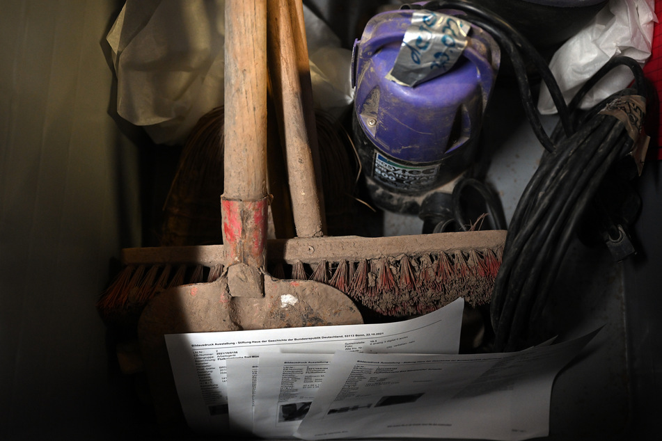 Schaufeln, Besen und eine Tauchpumpe, die von Helfern im Ahrtal benutzt wurden, stehen im Depot in einer Kiste.