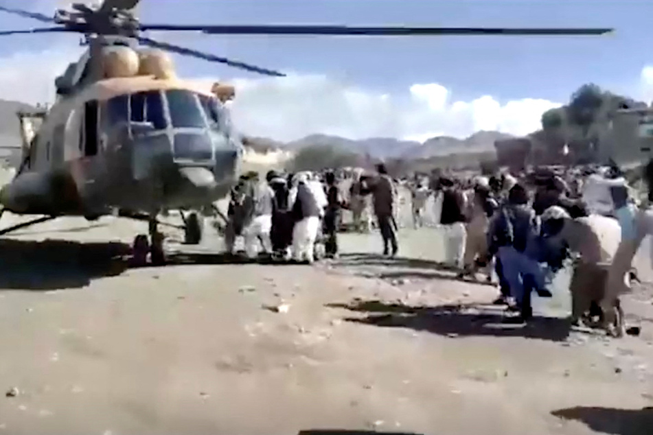 Locals help carry injured people to a rescue helicopter after the 6.1-magnitude quake.