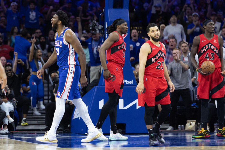 Joel Embiid celebrates as the Raptors players look dejected.