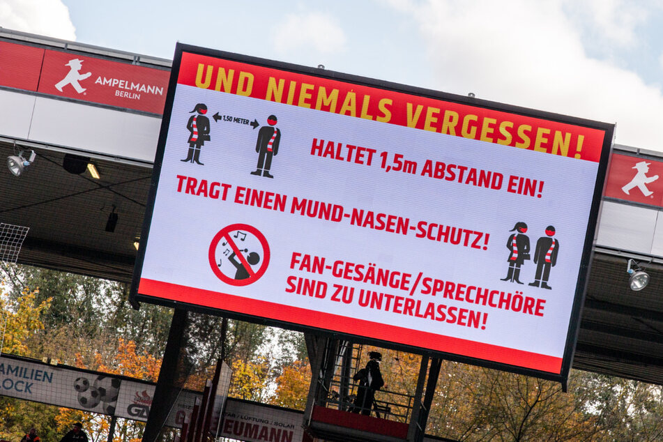Die Leinwand im Stadion An der Alten Försterei in Berlin zeigt den Schriftzug: Und niemals vergessen! Haltet 1,5m Abstand ein! Tragt einen Mund-Nasen-Schutz! Fan-Gesänge / Sprechchöre sind zu unterlassen!