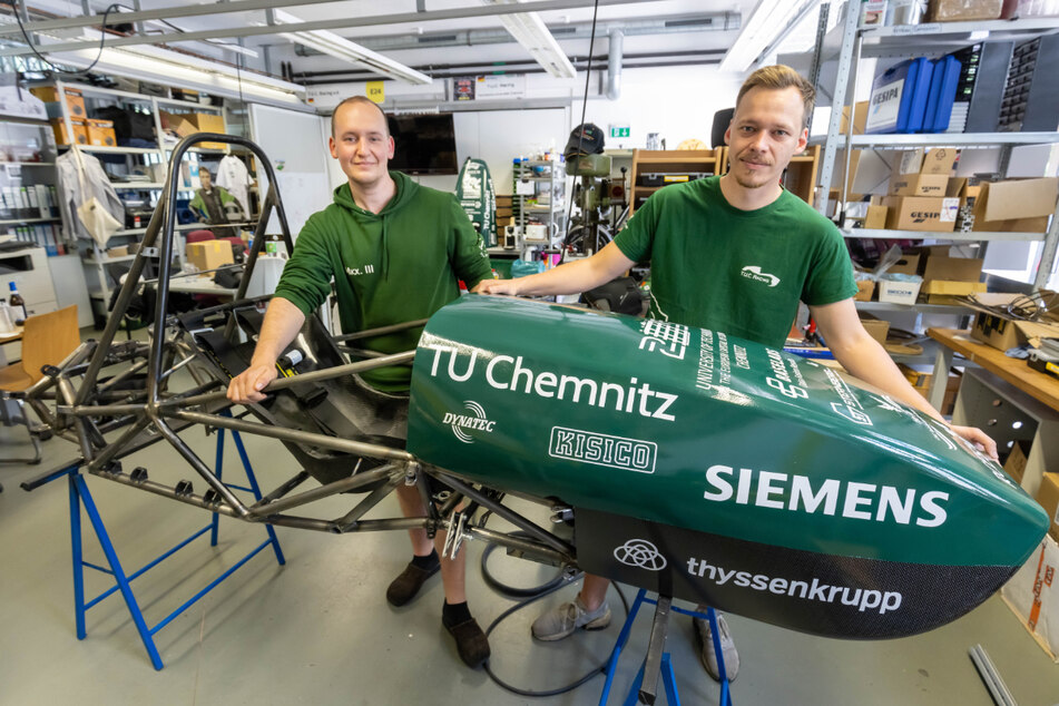 Norman Kästle (27, r.) und Marian Buder (24) von "T.U.C. Racing" bringen die Verkleidung an das Fahrzeug an.