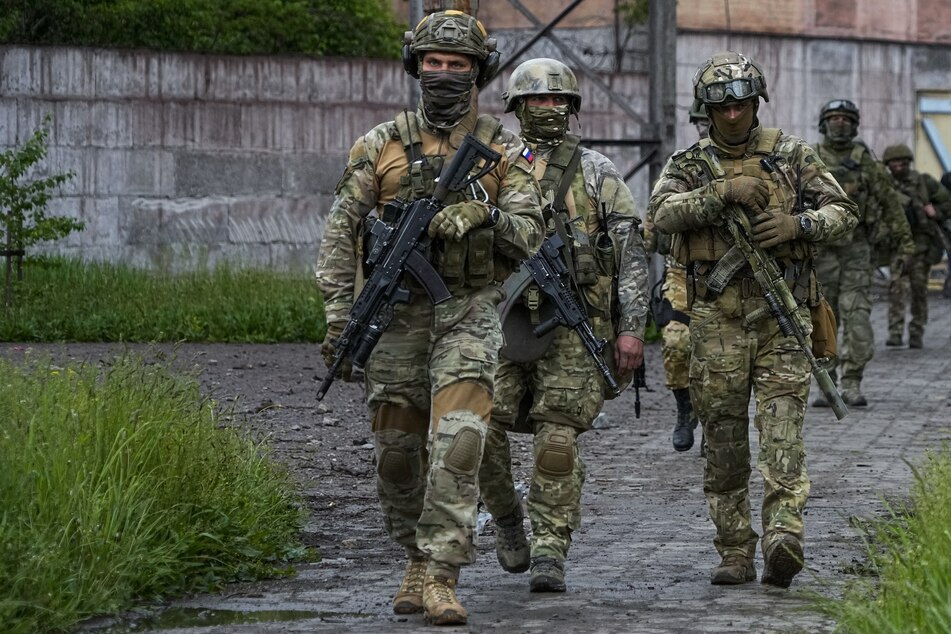 Russische Soldaten gehen durch einen zerstörten Bereich des Iljitsch Eisen- und Stahlwerks Mariupol.