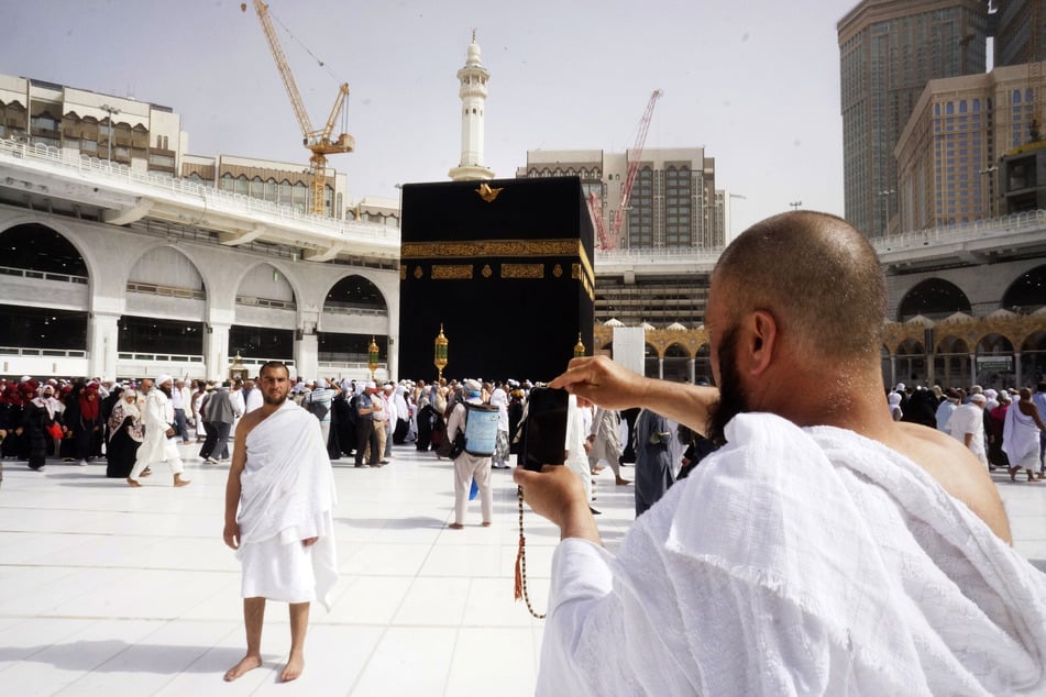 Saudi-Arabien, Mecca: Ein Pilger posiert für ein Foto vor der Kaaba in der Heiligen Moschee, während der kleinen Pilgerfahrt, bekannt als Umrah.