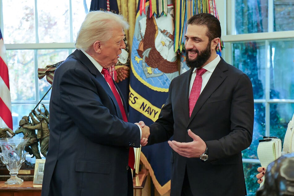 This handout photograph released by the official Syrian Arab News Agency (SANA) on Monday, shows President Donald Trump (L) shaking hands with Syria's President Ahmed al-Sharaa (R) at the White House in Washington DC.