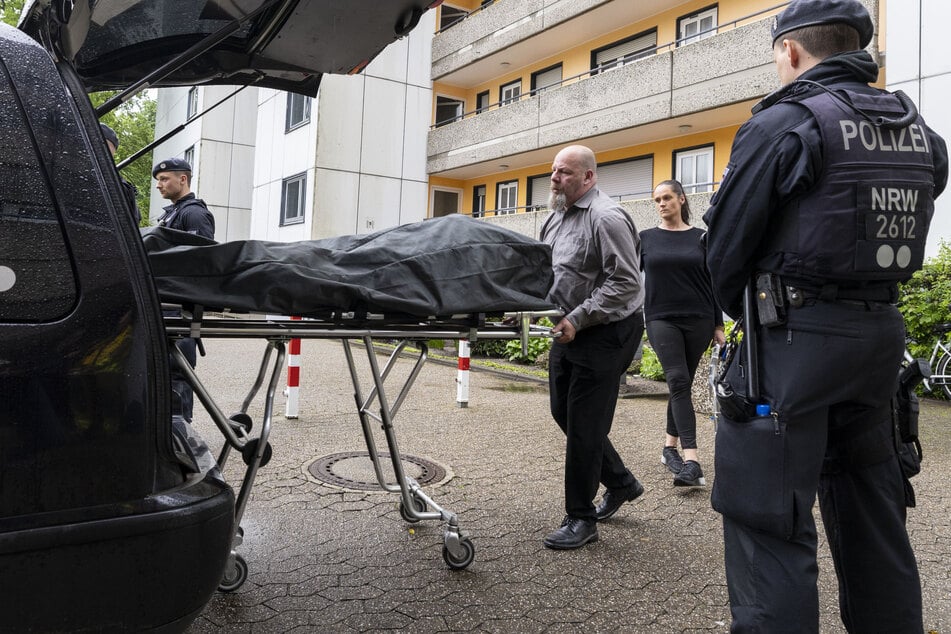 Bestatter bringen den Leichnam einer in der betroffenen Wohnung aufgefundenen Person zum Leichenwagen.