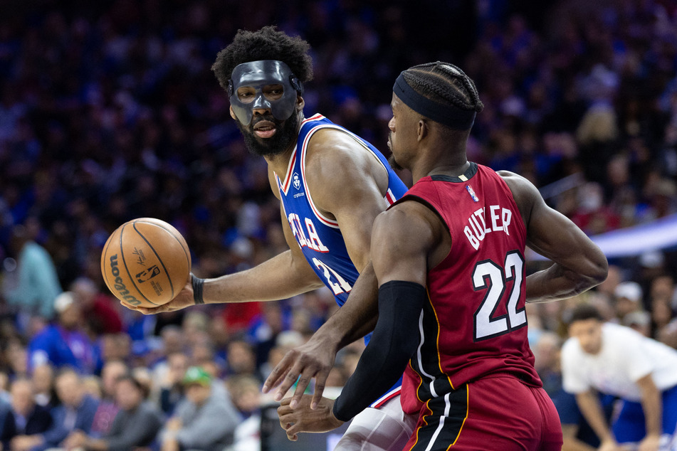 76ers center Joel Embiid (l.) controls the ball against Heat forward Jimmy Butler.