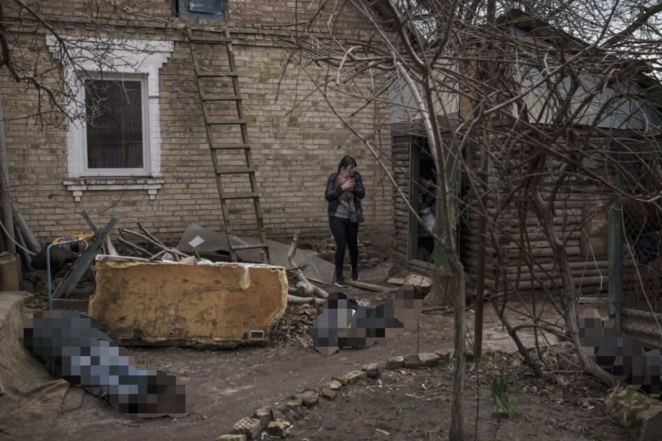 Ira Gavriluk hält ihre Katze, während sie zwischen den Leichen ihres Mannes, ihres Bruders und eines weiteren Mannes steht, die vor ihrem Haus in Butscha, am Stadtrand von Kiew, getötet wurden.
