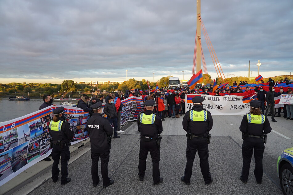 Polizisten stehen vor den Demonstranten, die sich mitten auf der Autobahn aufgestellt haben.