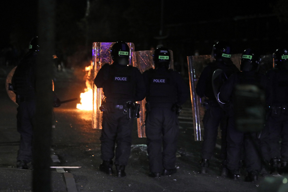 Polizisten mit Schutzschilden stehen in einer Straße in der Tigers Bay in Belfast während weiterer Unruhen, bei denen inzwischen Dutzende Beamte verletzt wurden.