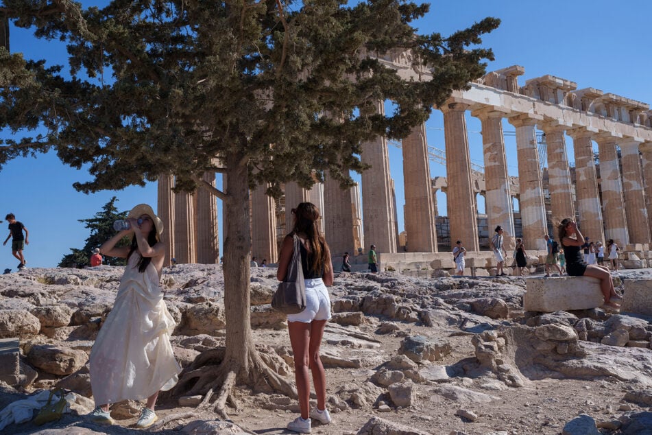 Urlauberinnen vor dem antiken Parthenon-Tempel auf dem Akropolis-Hügel. Wegen hoher Temperaturen wurden einige archäologische Stätten Griechenlands kürzlich geschlossen.