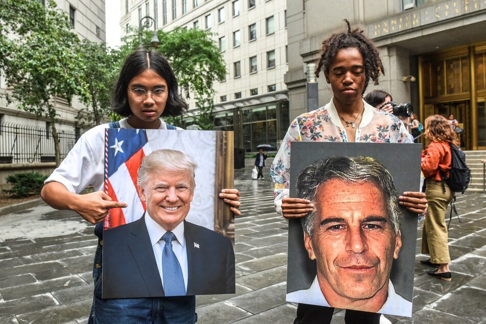 A protest group called "Hot Mess" hold up signs of Jeffrey Epstein and President Donald Trump in front of the Federal courthouse on July 8, 2019 in New York City.