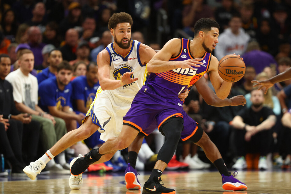 Phoenix Suns guard Devin Booker moves the ball against Golden State Warriors guard Klay Thompson in the second half at Footprint Center.