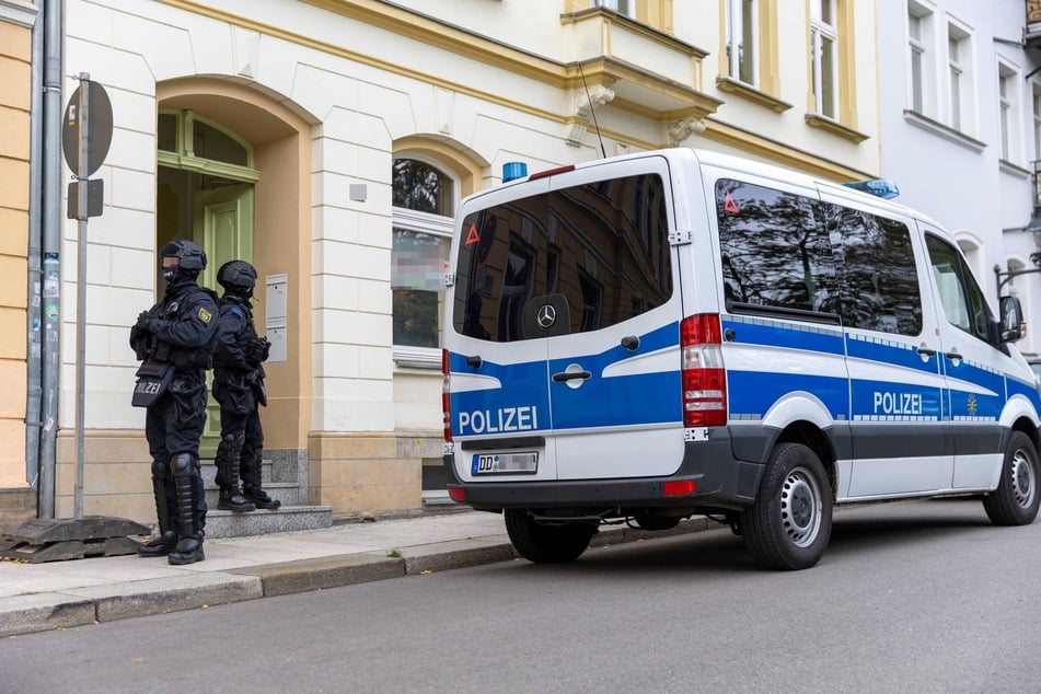 Schwer bewaffnete Beamte stehen vor einem Gebäude in Freiberg: Am gestrigen Mittwoch durchsuchte die Polizei Wohnungen und Büroräume.