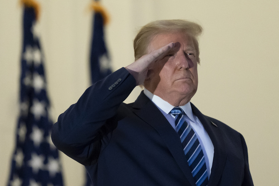 Präsident Donald Trump salutiert auf dem Balkon des Blue Room bei seiner Rückkehr in das Weiße Haus am Montag, nachdem er das Walter Reed National Military Medical Center in Bethesda, Md. verlassen hat.