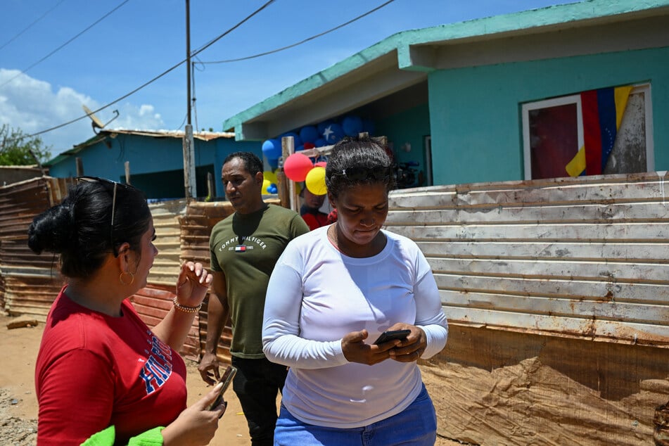Mercedes Yamarte (r.) uses her cellphone as she awaits the arrival of her son, Mervin Yamarte, who was repatriated from a jail in El Salvador, at their home in Maracaibo, Venezuela, on July 20, 2025.