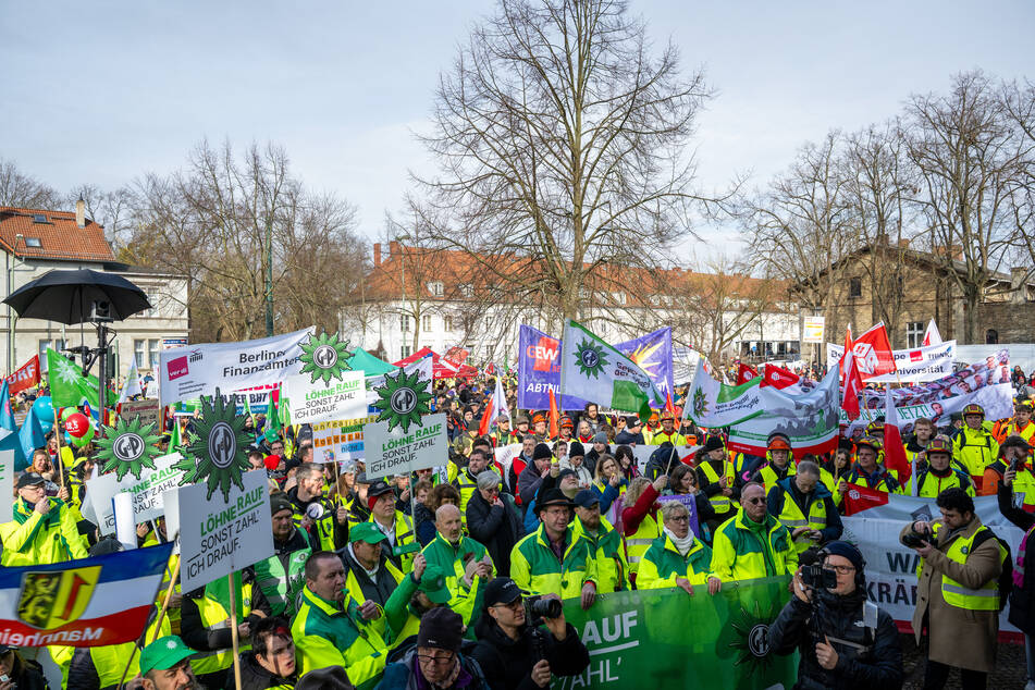 Demonstranten protestieren am Verhandlungsort in Potsdam mit Plakaten, darunter "Löhne rauf, sonst zahl ich drauf."