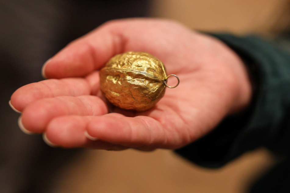 In einer geöffneten Hand liegt eine goldene Walnuss.