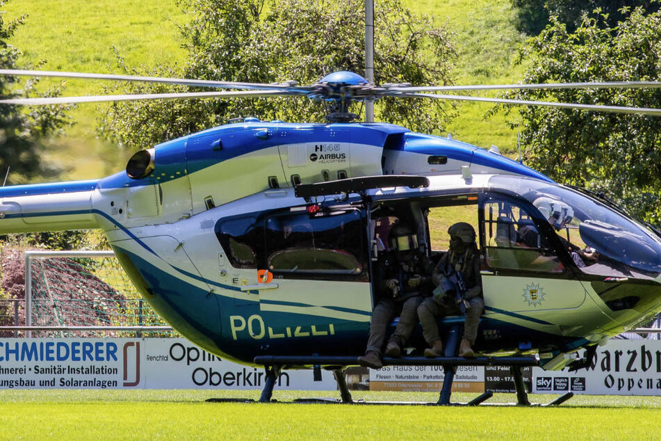 Polizisten eines SEK sitzen in der Tür eines gerade gelandeten Hubschraubers.