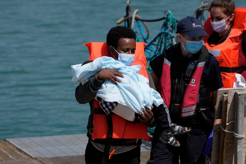 Ein Migrant hält ein Kind im Arm, während er im Hafen von Dover ankommt.