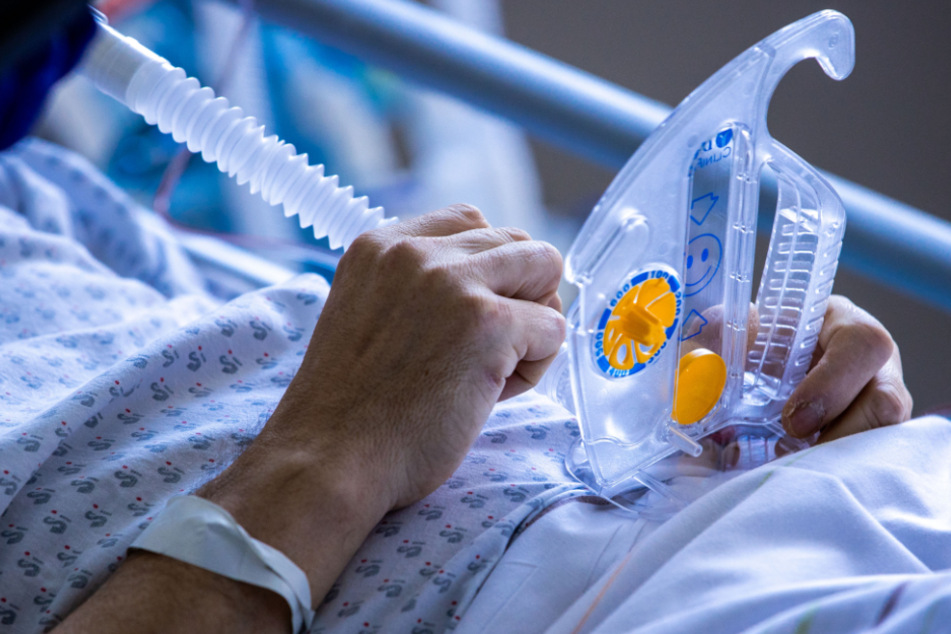 Ein Gerät für das Atemtraining hält ein an Corona erkrankter Patient im besonders geschützten Teils der Intensivstation des Universitätsklinikums Greifswald in den Händen.