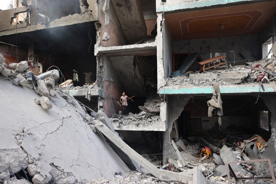 Palestinian children search through the rubble of their home in the Nuseirat refugee camp.