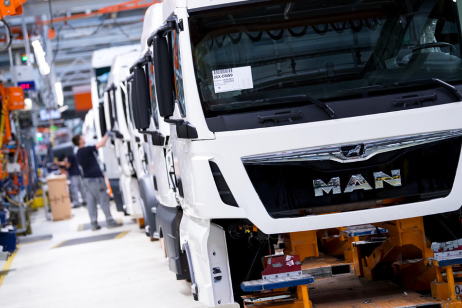 Mitarbeiter arbeiten an einer Produktionsstraße an einem LKW. Der Lastwagenbauer MAN will sich neu aufstellen und deshalb in Deutschland und Österreich bis zu 9500 Stellen abbauen.