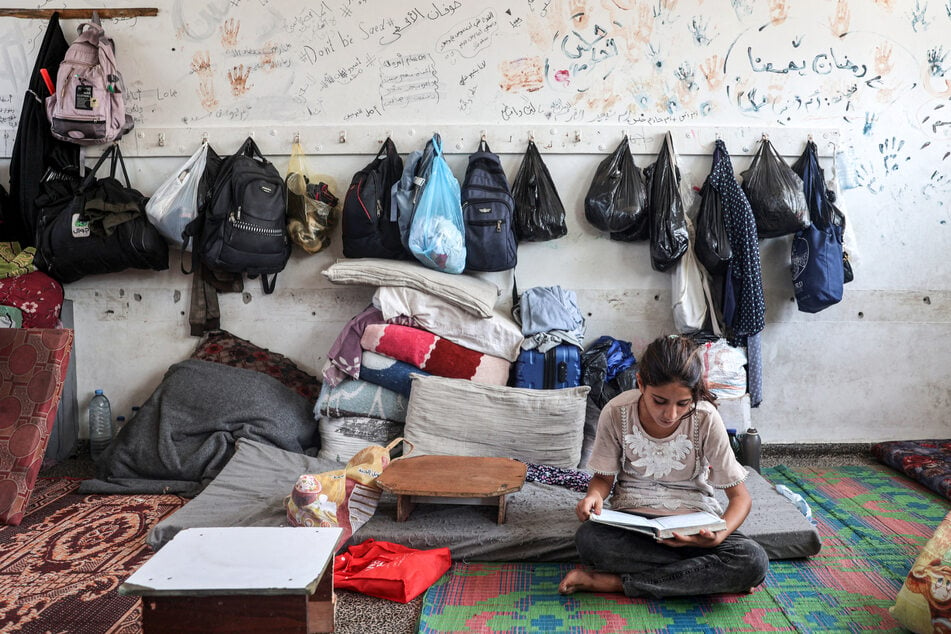 A girl reads from a textbook in a classroom sheltering people displaced by conflict at a school run by the UNRWA in Deir el-Balah in the central Gaza Strip on September 9.