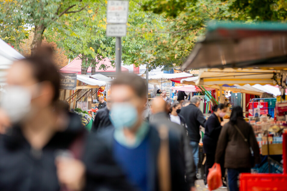 Menschen tragen Mund-Nasen-Bedeckungen und gehen in Berlin-Kreuzberg über den Markt am Maybachufer. Die Infektionszahlen in der Bundeshauptstadt steigen wieder.