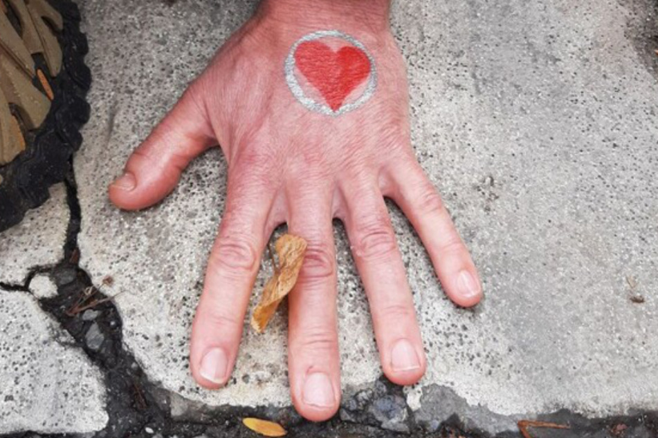 Die Hand eines Klimaaktivisten ist mit Kleber auf dem Berliner Asphalt befestigt.