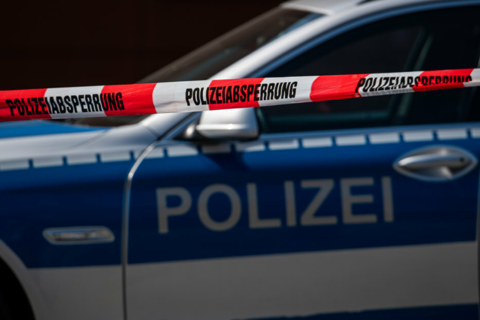 Ein Polizeiauto steht hinter einem Absperrband der Polizei. (Archivbild, Symbolbild)