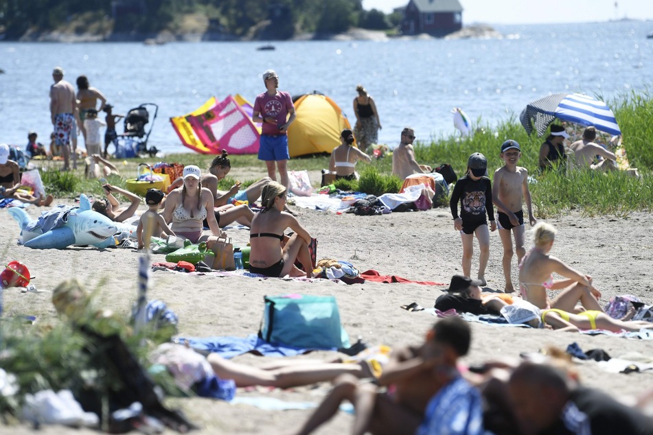Menschen genießen den heißen, sonnigen Tag an einem Strand in Helsinki.