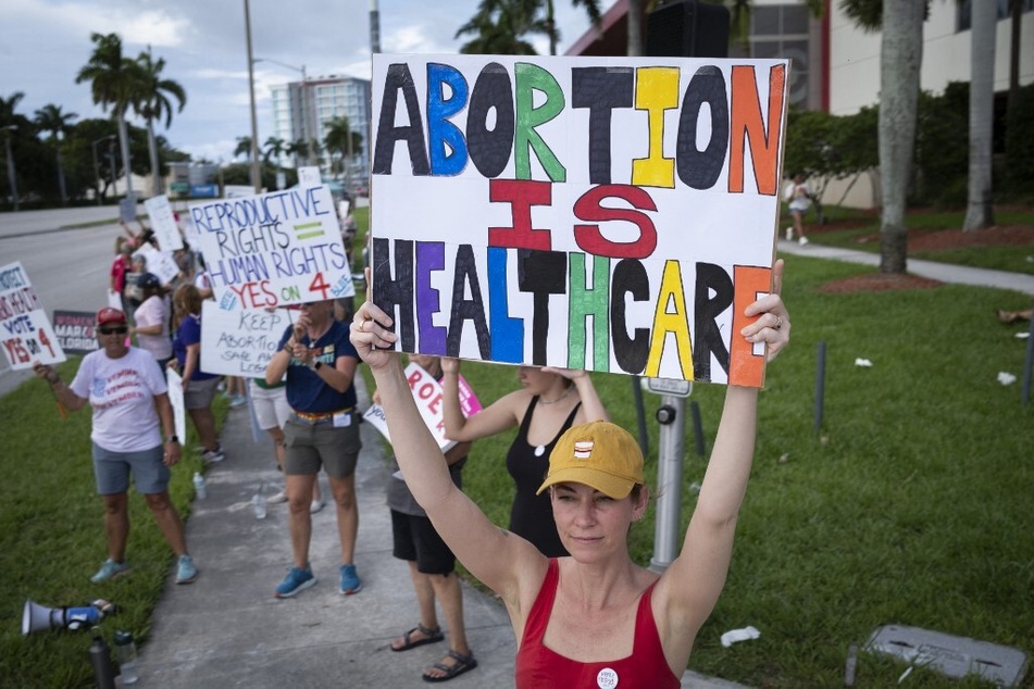 Demonstrators hold up signs during a pro-abortion rights rally on the second anniversary of the Supreme Court ruling to overturn Roe v. Wade, in West Palm Beach, Florida.