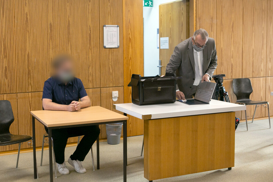 Der Angeklagte sitzt im Sitzungssaal vom Landgericht neben seinem Anwalt.