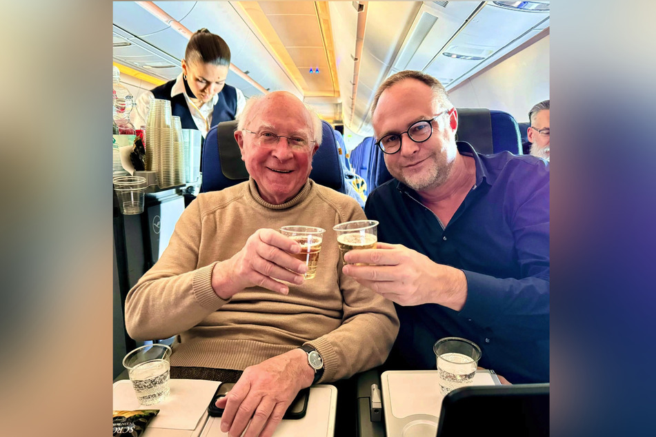 Vater Ernst (l.) stößt mit Sohn Konrad im Flieger auf die lang ersehnte Japan-Reise an.