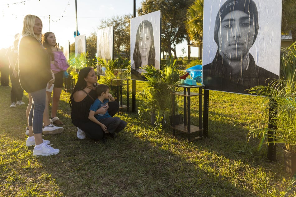Mariana Rocha (C), holds her son Jackson as she observes a photo of her cousin Joaquin Oliver (R) at a memorial on the fifth anniversary of the Marjory Stoneman Douglas High School mass shooting at Pine Trails Park on February 14, 2023 in Parkland, Florida.