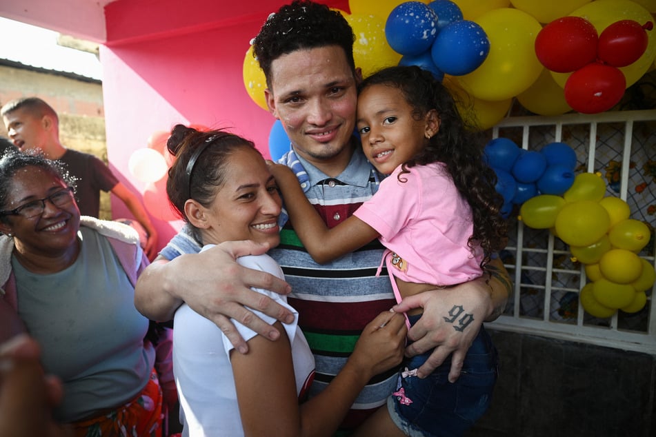 Mervin Yamarte (c.) is welcomed by his wife and their daughter upon arrival at his home in Maracaibo, Venezuela, on July 22, 2025.