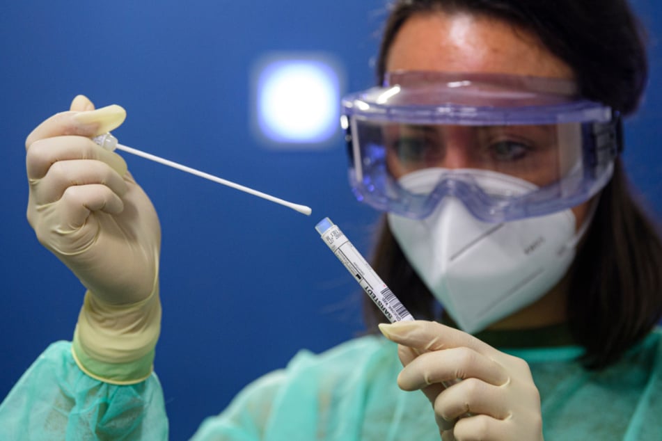 Eine Ärztin der Kassenärztlichen Vereinigung Sachsen hält in der Corona-Teststation für Urlaubsrückkehrer am Flughafen Dresden International einen Abstrich für einen Coronavirus-Test in den Händen.