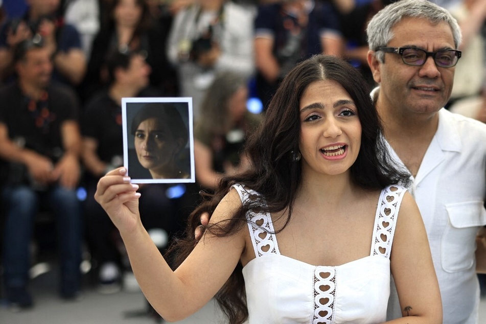 Iranian actor Setareh Maleki holds a portrait of fellow actor Soheila Golestani as she stands next to director and producer Mohammad Rasoulof.
