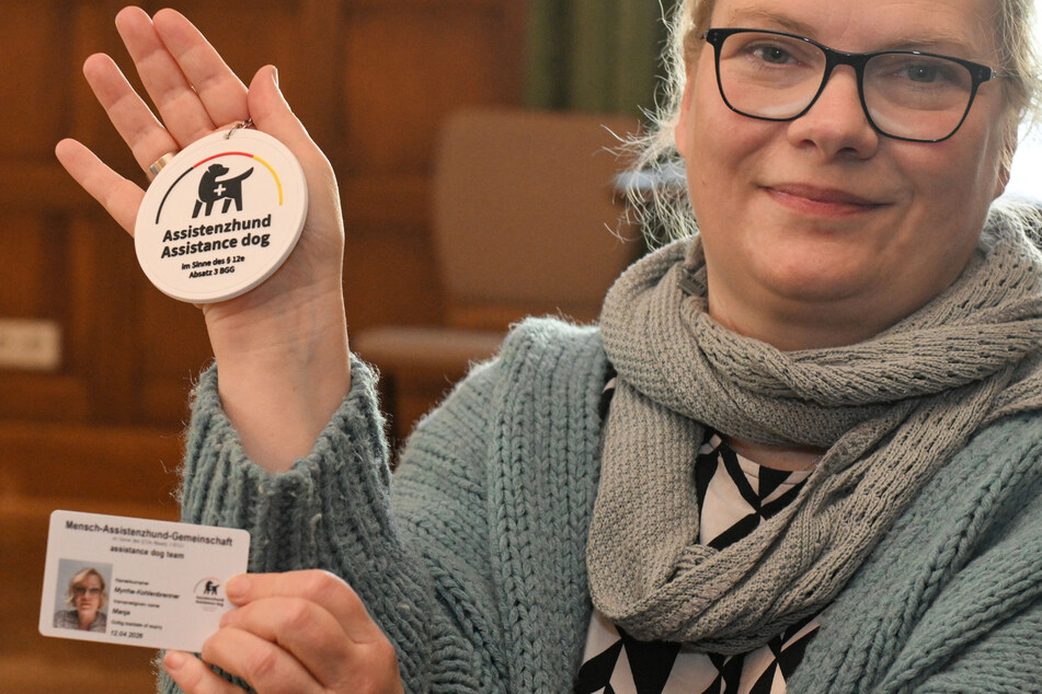 Mania Myrrhe-Kohlenbrenner (50) zeigt Ausweis und Plakette ihres Assistenzhundes.