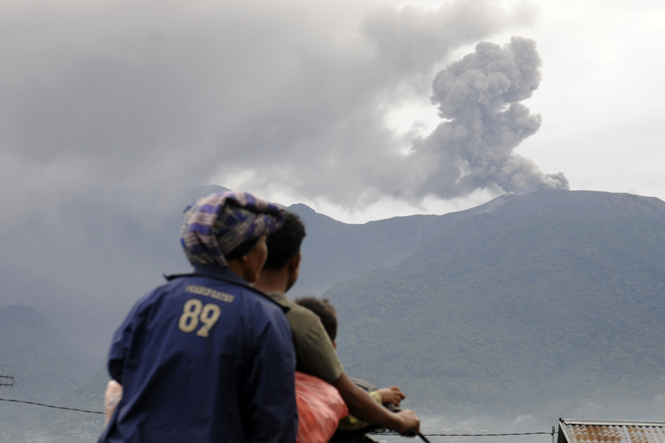 Rollerfahrer blicken auf Marapi, der nach dem Ausbruch vulkanisches Material ausspeit.