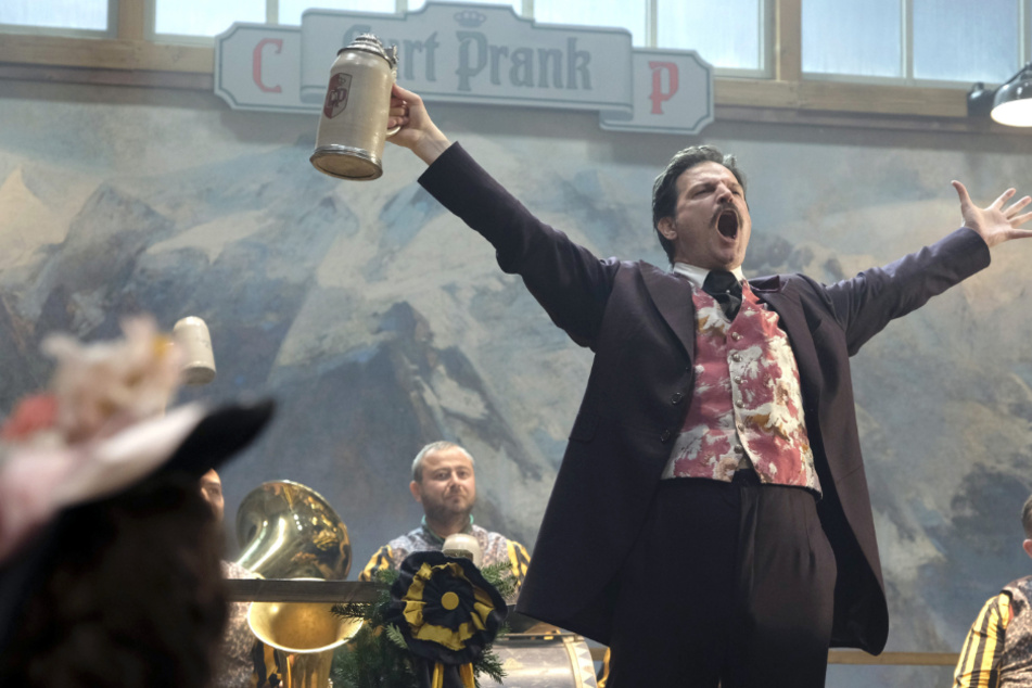 Curt Prank (Misel Maticevic) feiert sich in der vierten Folge, "Anstich", der Serie "Oktoberfest 1900" selbst vor der Blaskapelle in seiner Bierburg auf dem Münchner Oktoberfest.