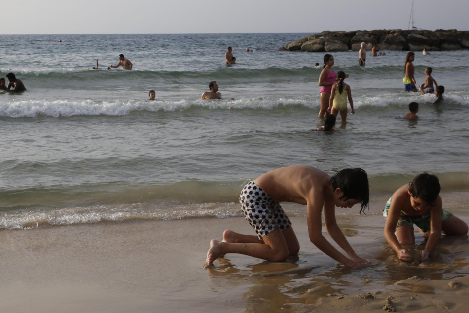 Israel, Aschkelon: Zwei Kinder buddeln am Strand. Der einmonatige landesweite Lockdown zur Eindämmung der Corona-Pandemie wurde aufgehoben.