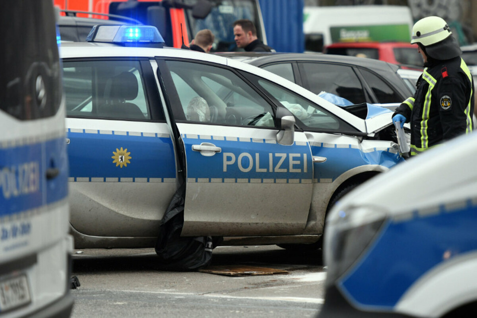 Ein Feuerwehrmann steht nach einem Unfall an einem beschädigten Polizeiauto.