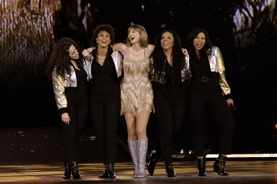 Taylor Swift smiles with her backup singers during the Fearless era on The Eras Tour.