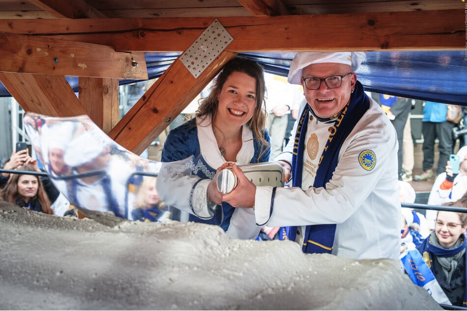 Stollenmädchen Lorna Prenzel (l.) und Bäckermeister Steffen Böhme (r.) schneiden den Riesenstollen mit einem 1,60 Meter langen Messer an.